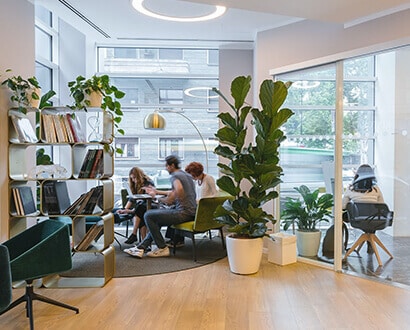 Paid social media strategists sitting at tables in a room with a bookshelf and plants